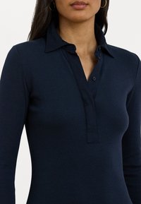 Námořnický proužkovaný polo tričko s límcem, knoflíkovou légou a dlouhými rukávy; hladká textura a přiléhavý design.
