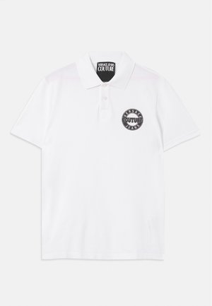Biela polokošela s krátkymi rukávmi a golierom, dvoma gombíkmi a okrúhlym čiernym logom "Versace Jeans Couture" na ľavej hrudi.