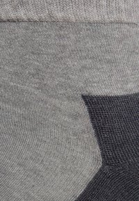 Calcetines grises y azul oscuro con una textura suave, que presentan un diseño acanalado, un distintivo bloque de colores y una zona del dedo del pie sin costuras.