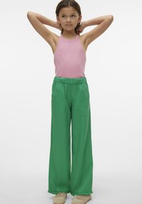 Różowy prążkowany top na halter i zielone spodnie o szerokich nogawkach z elastycznym paskiem. Lekka tkanina, teksturowany wzór oraz falbany na kostkach spodni.