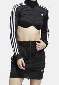 Black athletic set featuring a cropped zip-up jacket with white stripes and a coordinating skirt with an elastic waistband and zipper.