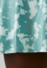 Világoskék sport szoknya, amelyen különböző árnyalatú batikolt minta található. Az alján egy apró, fehér Nike logó hímezve.