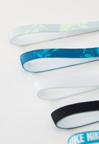 Nike trake, izrađene od tkanine u plavoj, bijeloj i crnoj boji. Neki imaju cvjetne uzorke; drugi su jednobojni. Teksturirani, elastični materijal.
