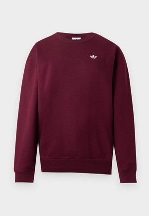Tamnoljubičasti dugi rukav s okruglim izrezom, rebrasti rukavi i rub, s malim bijelim Adidas trefoil logom na lijevoj strani prsnog koša.