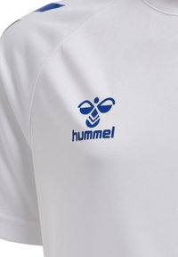 Camiseta deportiva blanca con el logo azul "hummel" y un diseño estilizado. Fabricada con material sintético suave, cuenta con mangas cortas y un cuello redondo.