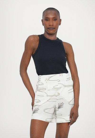 Μαύρο αμάνικο τοπ σε συνδυασμό με λευκές βερμούδες που διαθέτουν πράσινες αφηρημένες γραμμές και λουλουδάτα σχέδια, και τα δύο κατασκευασμένα από ελαφρύ ύφασμα.