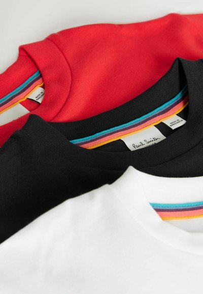 Set aus vier T-Shirts in Rot, Schwarz, Weiß und mit grauem Hintergrund. Jedes hat einen gerippten Kragen mit mehrfarbigen Streifen.