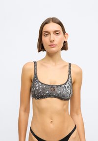 Μπικίνι τοπ με λεοπάρ σχέδιο, τετραγωνισμένο ντεκολτέ, λεπτές τιράντες και μικρή λεπτομέρεια λογότυπου, σε συνδυασμό γκρι και μαύρων αποχρώσεων.