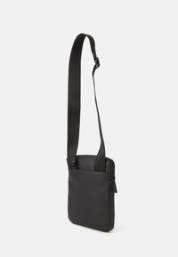 Svart axelväska med en rektangulär form, texturerad yta, justerbar rem och ett fack med dragkedja för säker förvaring.