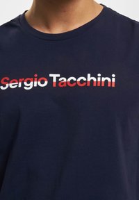 Mørkeblå bomulls t-skjorte med et fremtredende logo i hvitt, rødt og mørkeblått, med en klassisk rund halsdesign og en myk tekstur.