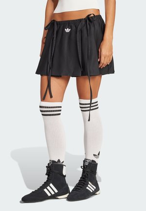 Black athletic skirt with a drawstring waist, paired with white knee-high socks featuring black stripes and black athletic shoes with white accents.