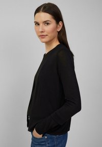 Zwarte cardigan van lichtgewicht stof, met een ronde halslijn, lange mouwen en een eenvoudig, open voorkantontwerp.