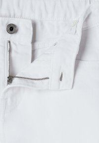 Vita denimjeans med silverfärgad dragkedja, knappstängning och subtilt texturerat tyg. Inkluderar en liten öppning nära dragkedjan.
