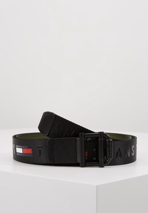 Musta kangasvyö mustalla metallisoljella, jossa on prässätty "JEANS"-teksti ja punainen, valkoinen ja sininen suorakaiteen muotoinen logotarra.