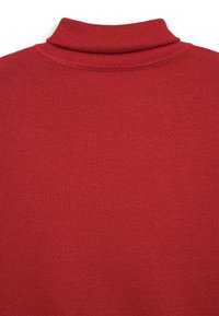 Pull à col montant rouge en tissu tricoté. Il présente un col côtelé et une texture lisse sans motifs ni accessoires visibles.