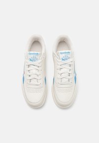 Sneakers Reebok in pelle bianca con dettagli azzurri, punta perforata, lacci piatti e interno imbottito. Logo classico sulla linguetta.