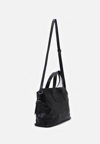 Sac à main en cuir noir texturé avec deux poignées courtes et une longue bandoulière réglable, sur fond blanc uni.