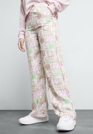 Pantalones de pierna ancha con un patrón en tonos pastel que presenta diseños geométricos en rosa, verde y beige. Hechos de un material suave, combinados con zapatillas blancas.