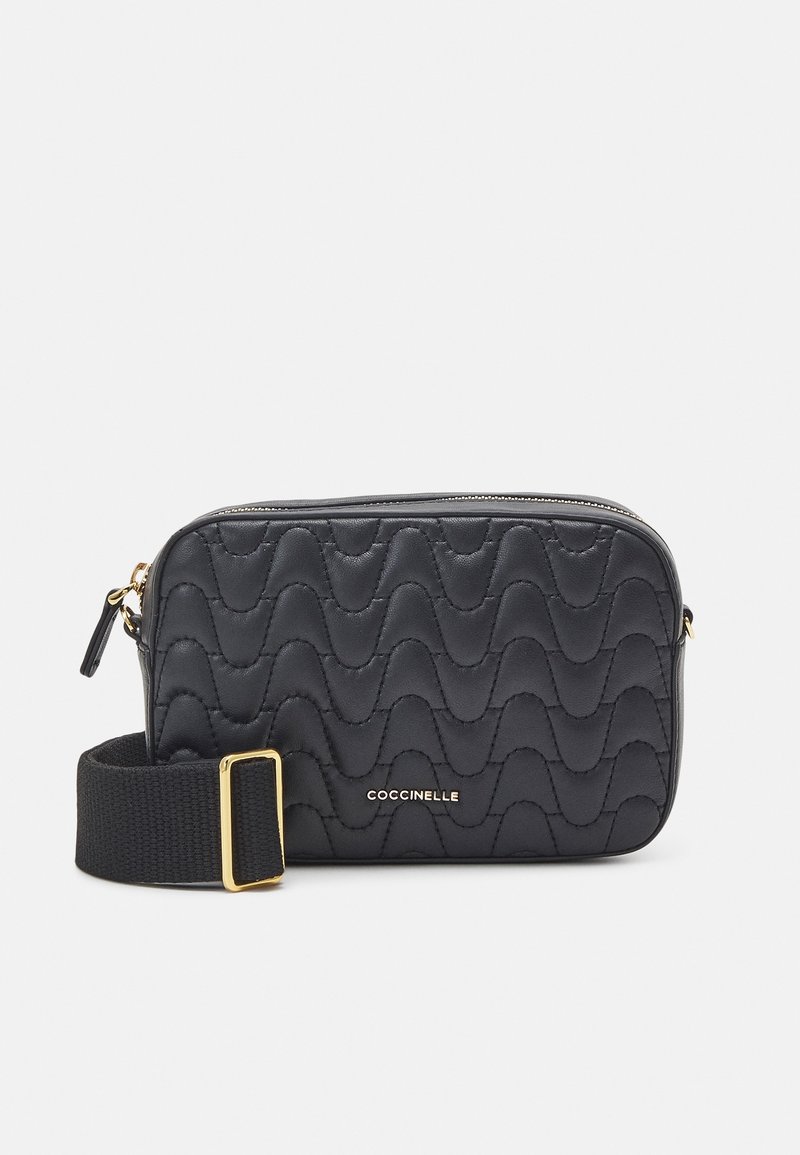 Bolso negro de cuero acolchado con cierre de cremallera, con patrones ondulados y una correa de tela con hebilla dorada. Logo de la marca visible.