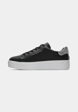 Black leather sneaker with a white platform sole, featuring flat laces, a silver accent on the heel, and embossed logo on the side.
