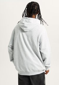 Lysegrå hoodie lavet af blødt stof, med snøre i hætten og ribbede manchetter. Glat tekstur, afslappet pasform og minimalistisk design.