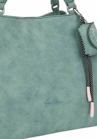 Un sac fourre-tout en simili cuir turquoise avec une texture lisse, doté de poignées enroulées, d'un pompon décoratif et de détails de logo discrets.