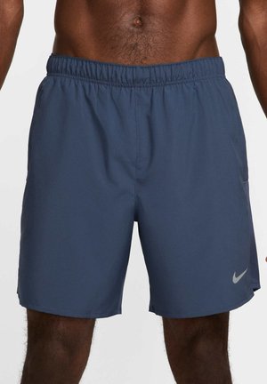 Man draagt marineblauwe sportshorts met elastische tailleband en Nike-logo op het linkerbeen, toont torso en bovenbenen.