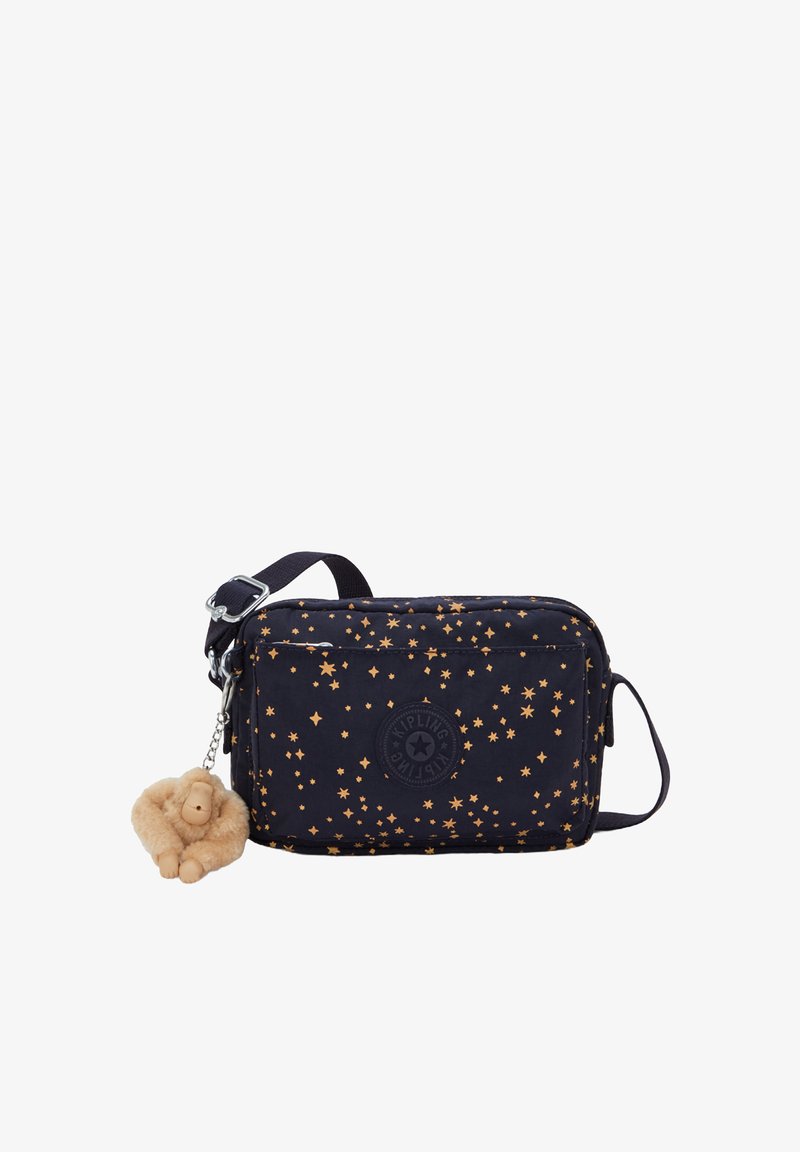 Navy fabric crossbody bag with gold star pattern, zip closure, adjustable strap, and a plush monkey keychain attached.