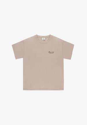 Beżowy bawełniany t-shirt z krótkimi rękawami, okrągłym dekoltem i subtelnym ciemnym napisem "Pride 1999 Teamwear" na lewej piersi.