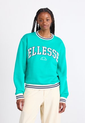 Lys teal sweatshirt med ribbet navy og hvid krave og manchetter. Har "ELLESSE" broderet i kontrasterende farver hen over forsiden.