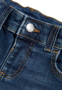 Jeans i denim med en mörkblå tvätt, med guldstickningar, en metallknappsstängning och en klassisk midjebandsdesign.