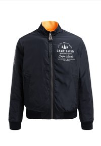 Schwarze Bomberjacke aus Nylon mit orangefarbenem Innenfutter, Reißverschluss, gerippten Bündchen und bedruckten Grafiken auf Brust und Ärmel.