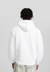 Weißer Kapuzenpullover aus weichem Stoff, mit einer lockeren Passform, gerippten Bündchen und einer Kängurutasche für zusätzlichen Detailreichtum.