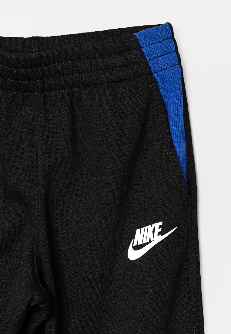 Pantalons de sport noirs avec une accentuation bleue sur la taille, dotés d'une taille élastique et d'un logo Nike blanc sur le côté gauche.