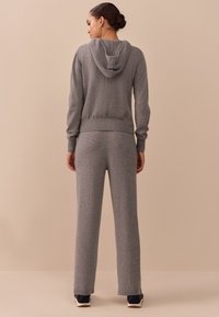 Gray knit hoodie with a front pocket and ribbed cuffs, paired with matching gray sweatpants, both featuring a soft texture and relaxed fit.