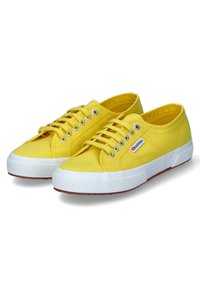 Sneakers in tela gialla con suola in gomma bianca, dotati di occhielli in argento, lacci piatti e tomaia testurizzata, progettati per un uso casual.