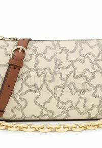 Bolso de piel beige con un patrón texturizado de líneas irregulares, correa ajustable marrón y un detalle de cadena dorada en la parte inferior.