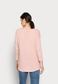 Top de malha rosa claro com padrão texturizado em riscas, mangas três quartos, decote largo e um ajuste descontraído.