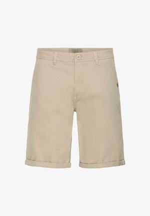 Pantalones cortos de algodón color beige con cierre de botones, puños enrollados y un detalle sutil de logo en el costado. Textura suave y diseño de pierna recta.