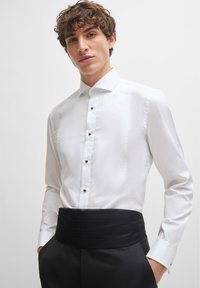 White dress shirt with a folded collar and black buttons, paired with a black fabric cummerbund, featuring smooth, sleek texture.