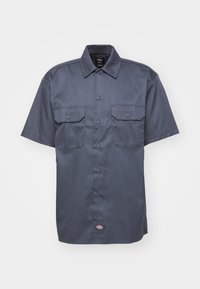 Chemise de travail gris foncé à manches courtes avec boutons, deux poches poitrine boutonnées et une petite étiquette logo à l’ourlet.
