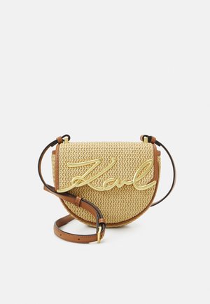 Vävd stråväska över kroppen med en böjd form, guld "Karl" logotyp, brunt läderkanter och justerbar rem.