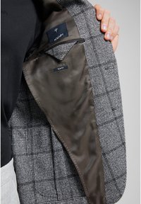 Marynarka slim fit w szarym wzorze houndstooth. Wnętrze wykończone jest gładką brązową podszewką oraz metkami, w tym "SLIM FIT" i "LOOP!" w kolorze niebieskim.