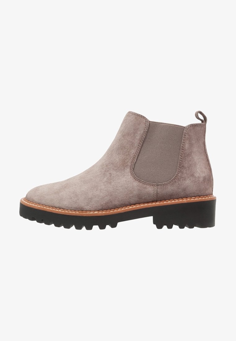 Bottine Chelsea en daim taupe avec un panneau latéral élastique, une languette au talon, une surpiqûre fauve et une semelle épaisse noire à crampons.