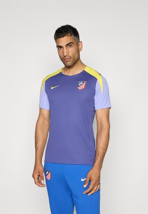 Lilla træningsshirt med korte ærmer, gule skulderdetaljer, med Nike-logoet og et klubemblem på brystet.