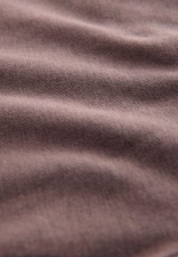 Material maro moale cu textură ușoară și elasticitate subtilă, prezentând falduri delicate și o suprafață netedă. Ideal pentru îmbrăcăminte sau tapițerie.