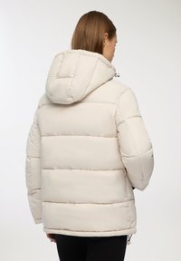 Giacca a vento in beige chiaro con cappuccio, dotata di sezioni trapuntate, una vestibilità rilassata e lacci regolabili in vita.