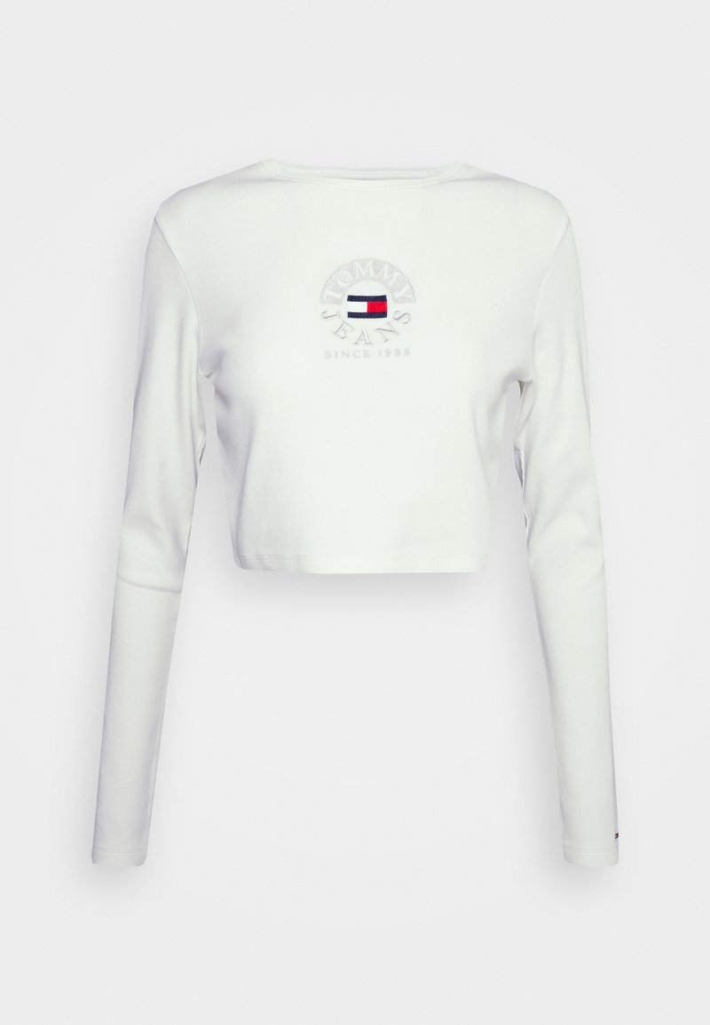 T-shirt blanc à manches longues écourtées en coton. Doté d'un logo brodé avec des accents rouges, blancs et bleus, et d'un col rond.