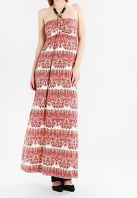 Robe maxi à design sans bretelles, ornée d'intricates motifs floraux rouges et dorés sur un fond blanc. Nouée au niveau du buste, en tissu doux.