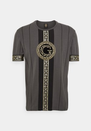 Camisa gris oscuro de manga corta con rayas negras verticales, patrón de greca griega dorada en el centro y en los puños de las mangas, y un emblema circular dorado.
